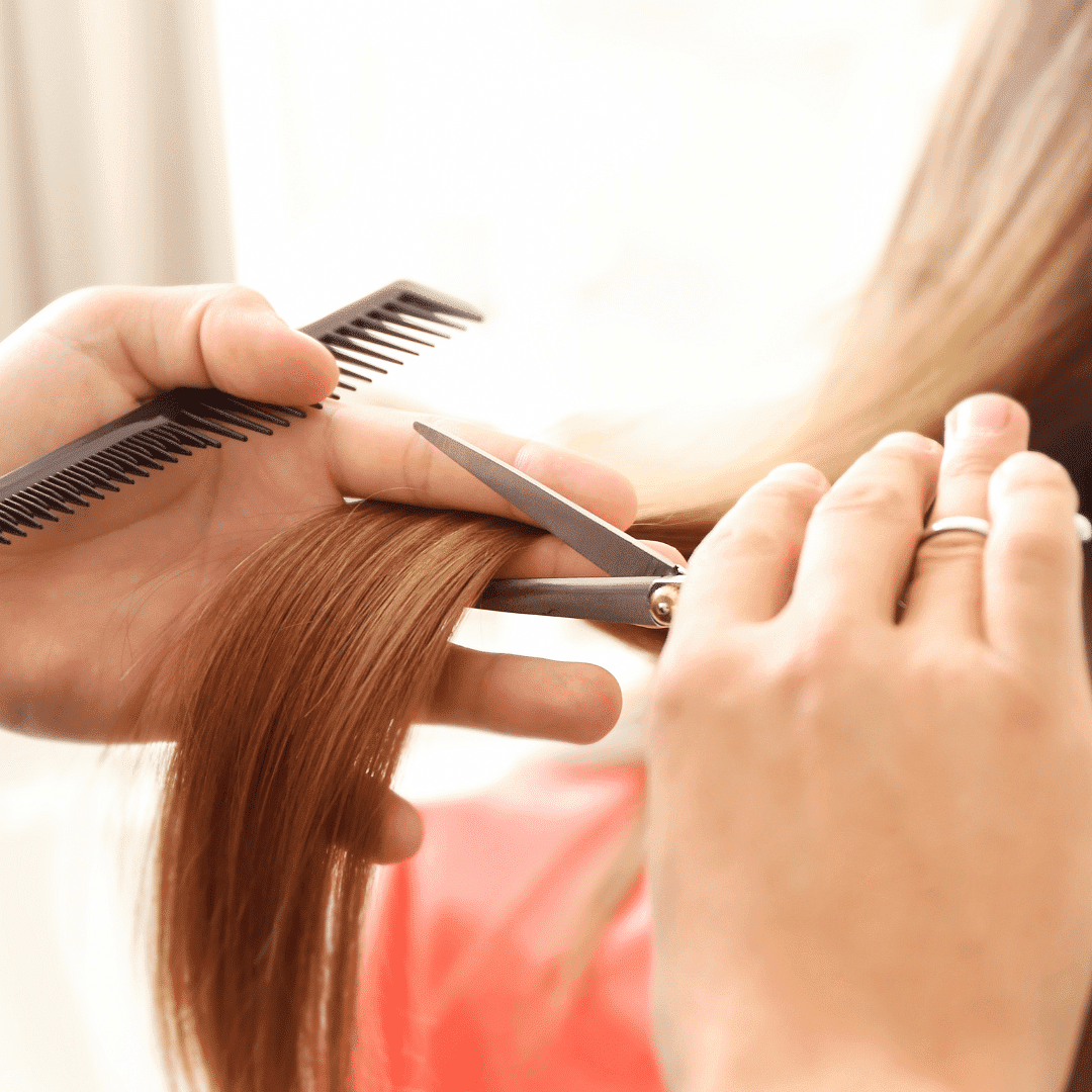 Hairdresser trimming a client's hair with scissors and comb.